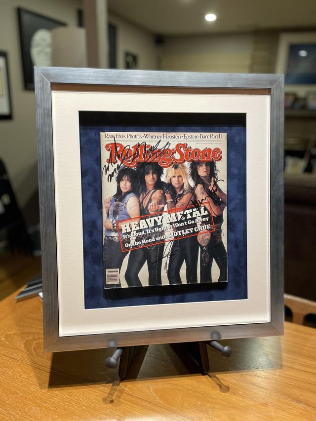 A Rolling Stone magazine cover in a silver frame with a blue mat, on a tabletop easel