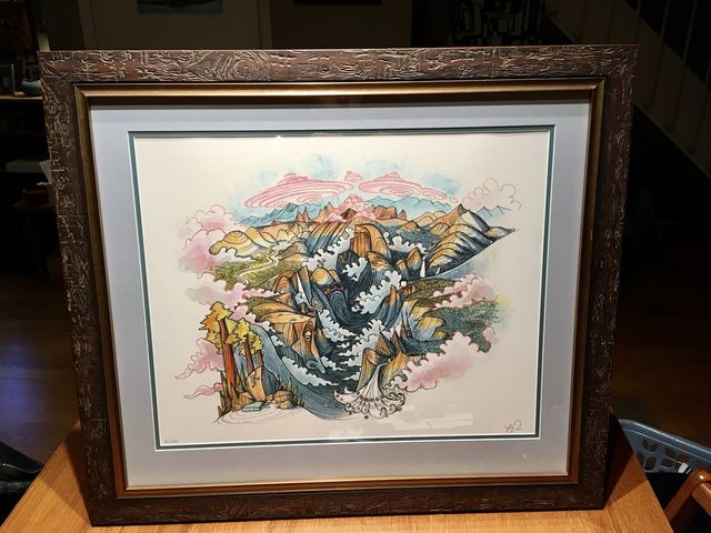 A loose watercolor in a carved dark wood frame with a gray mat