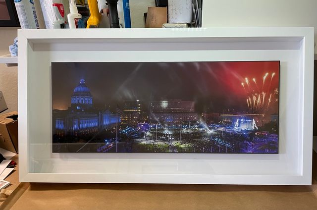 A panoramic night photo of a lit-up city with fireworks, in a deep white frame